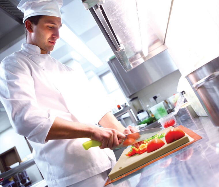 Chef cutting vegetables in professional kitchen